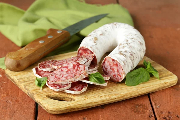 Delicatesse gerookte worst (salami) op een houten bord — Stockfoto