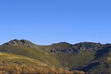 İspanya 'nın Zamora bölgesindeki güneşli bir kış gününde Rocky tepeleri yeşil çayırların üzerinde.