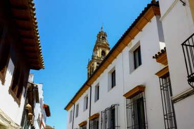 İspanya 'daki Cordoba Camii' nin çan kulesi güneşli bir yaz gününde şehrin beyaz evlerinin çatıları üzerinde.