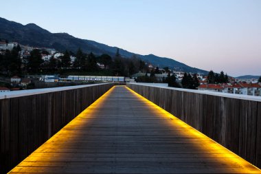 Covilha, Portekiz, 17 Mart 2014; Covilh 'deki Ribeira da Carpinteira üzerindeki Carrilho da Graa yaya köprüsünün ön görüntüsü gün batımında portakal ışığı ve arka plandaki dağlarla aydınlatıldı.