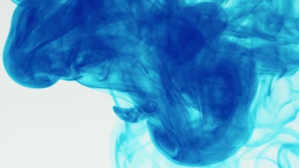 Eine Zeitlupenaufnahme blauer Flüssigkeit, die vor weißem Hintergrund ins Wasser fließt. Blaue Pigmenttinte Wasserexplosion von oben weißen Hintergrund.