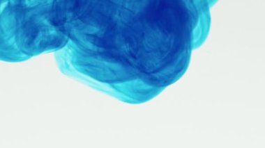 Mavi sıvının beyaz bir arkaplan üzerinden suya aktığı yavaş çekim. Beyaz arkaplandan mavi pigment mürekkep patlaması.