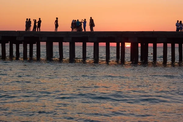 Ludzie na stare molo morze o zachodzie słońca — Zdjęcie stockowe