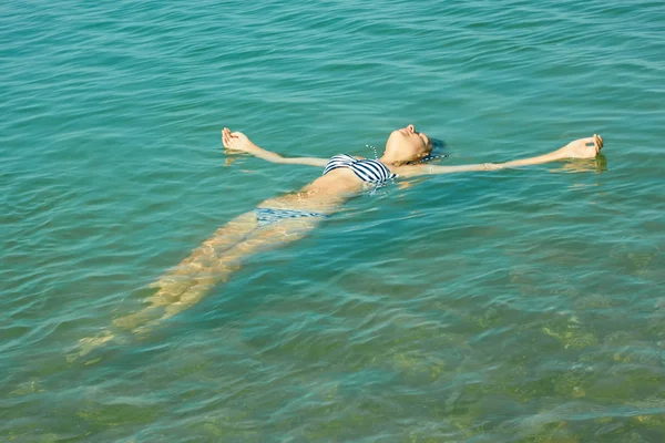 Menina adolescente deitada na superfície da água do mar — Fotografia de Stock