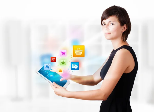 Mladá žena při pohledu na moderní tablet s barevnými ikonami — Stock fotografie