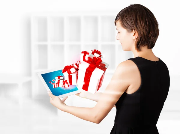 Junge Frau schaut auf modernes Tablet mit Geschenkschachteln — Stockfoto