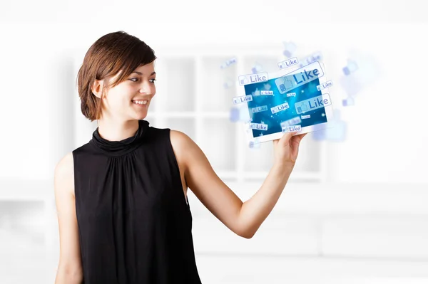 Young woman looking at modern tablet with social icons — Stock Photo, Image