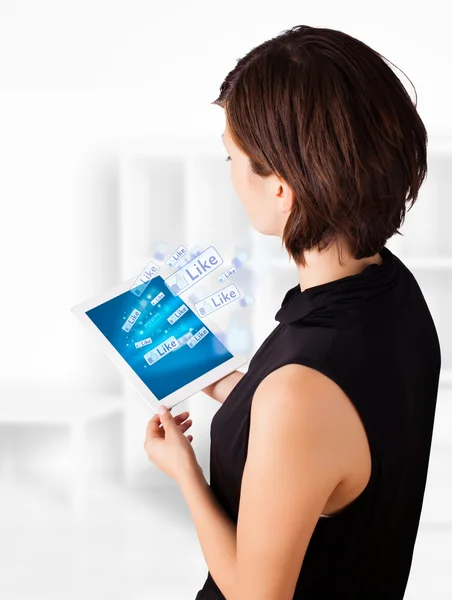 Young woman looking at modern tablet with social icons — Stock Photo, Image