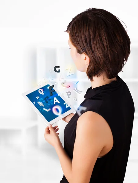Jovem mulher olhando para tablet moderno com alfabeto — Fotografia de Stock