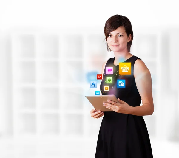 Mujer joven mirando el comprimido moderno con iconos de colores —  Fotos de Stock