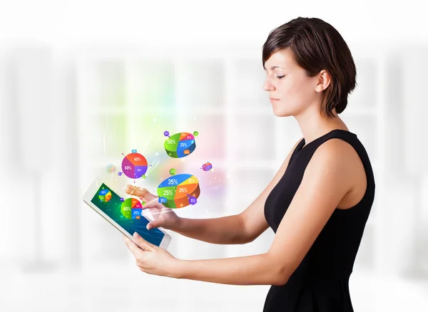 Mujer joven mirando la tableta moderna con gráficos de pastel —  Fotos de Stock