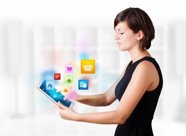Jovem mulher olhando para tablet moderno com ícones coloridos — Fotografia de Stock