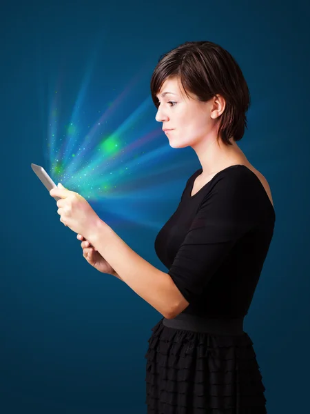 Молодая женщина смотрит на современный планшет с абстрактными огнями — стоковое фото