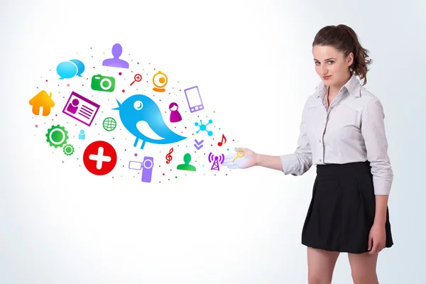 Young business woman presenting colourful social icons — Stock Photo, Image