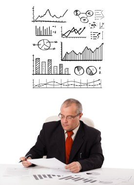 businessman sitting at desk with statistics and graphs