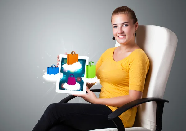 Vrouw met moderne tablet met kleurrijke boodschappentassen op wolk — Stockfoto