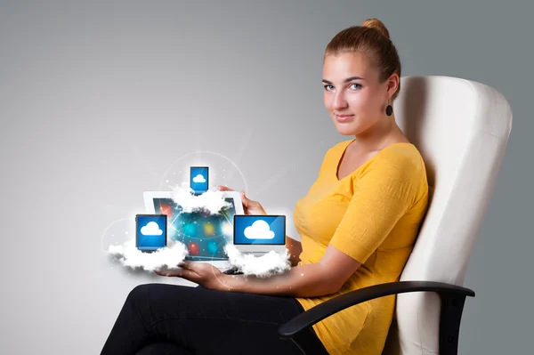 Junge Frau hält Tablet mit modernen Geräten in den Wolken — Stockfoto