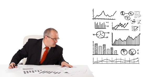 Businessman sitting at desk with statistics and graphs — Stock Photo, Image