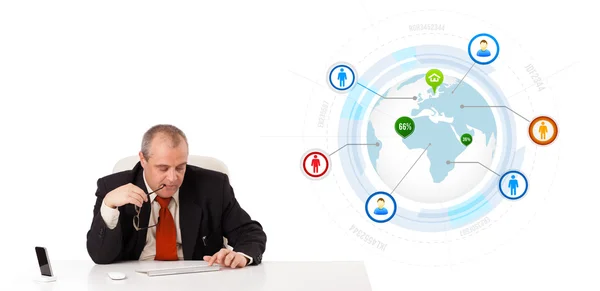 Geschäftsmann sitzt am Schreibtisch und tippt mit Globus auf Tastatur — Stockfoto