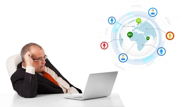 Zakenman aan bureau zitten en op zoek laptop met globe en zo — Stockfoto