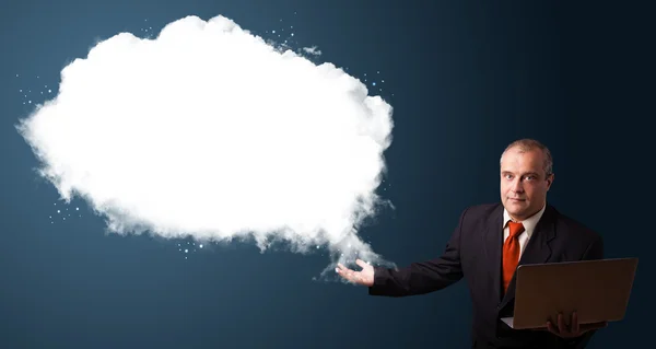 Empresário segurando um laptop e apresentando cópia em nuvem abstrata — Fotografia de Stock