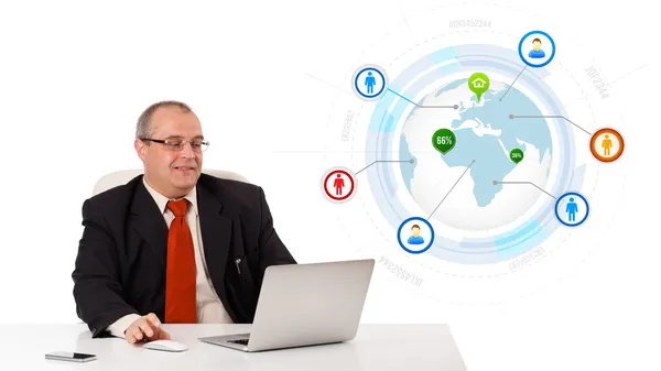 Businessman sitting at desk and looking laptop with globe and so Stock Picture