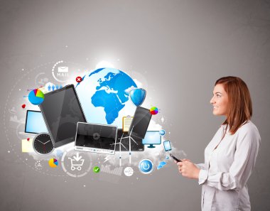 Genç bir kadın ayakta ve telefonunda geziniyor.