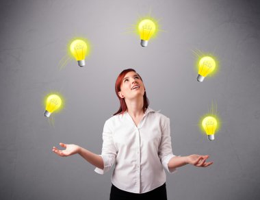 Genç bayan ayakta ve ampullerle hokkabazlık yapıyor.