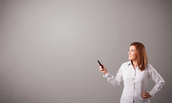 Giovane signora in piedi e in possesso di un telefono con spazio copia — Foto Stock