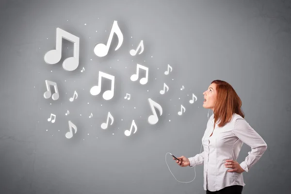 Jolie jeune femme chantant et écoutant de la musique avec n musical — Photo