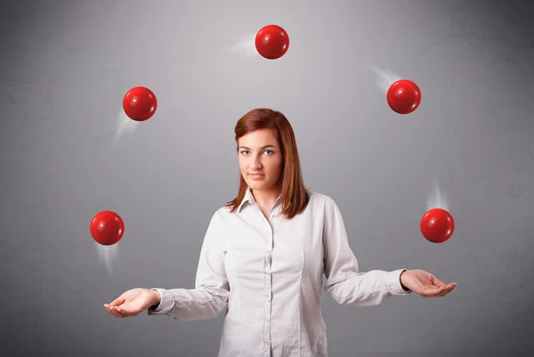 Junges Mädchen steht und jongliert mit roten Bällen — Stockfoto