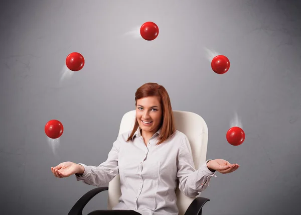 Молода дівчина сидить і жонглює з червоними кульками — стокове фото