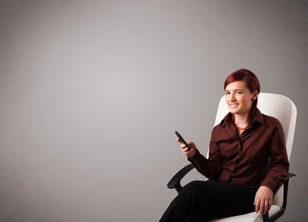 Young lady sitting and holding a phone with copy space — Stock Photo, Image