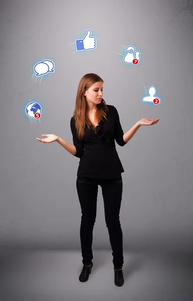 Приваблива молода жінка жонглює з іконками соціальної мережі — стокове фото