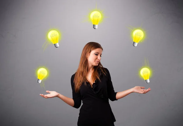 Young lady standing and juggling with light bulbs — Stock Photo, Image