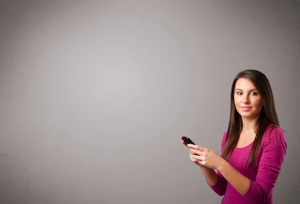 Young lady standing and holding a phone with copy space — Stock Photo, Image