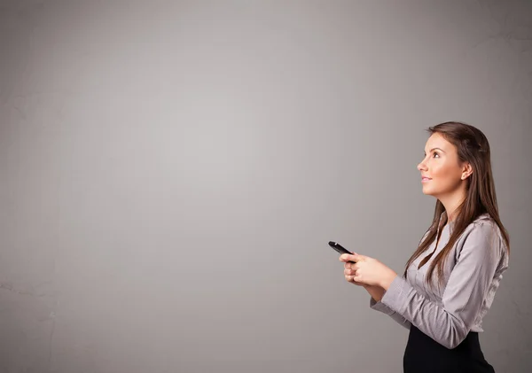 Jovem senhora de pé e segurando um telefone com espaço de cópia — Fotografia de Stock