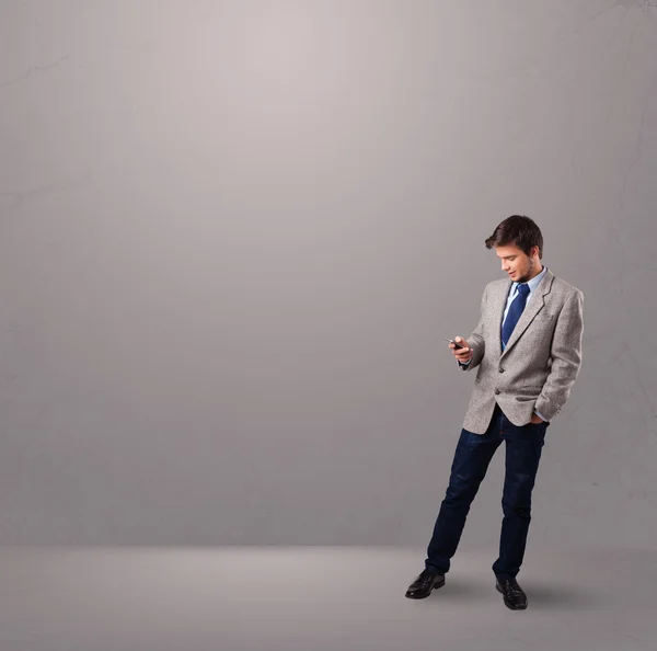 Przystojny chłopak stoi i trzymając telefon — Zdjęcie stockowe