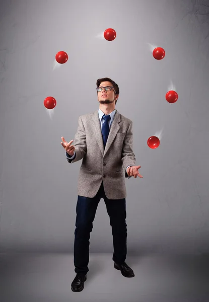 Jeune homme debout et jonglant avec des boules rouges — Photo