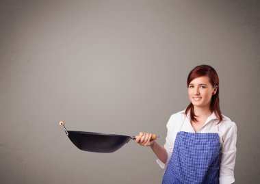 Genç bayan elinde kızartma tavası tutuyor.