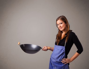 Genç bayan elinde kızartma tavası tutuyor.