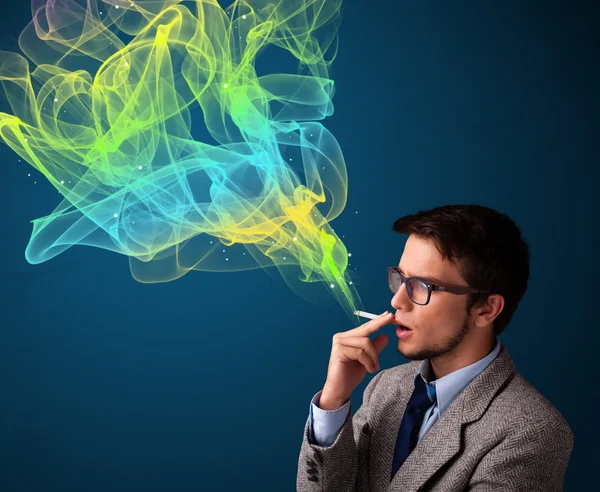 Homem bonito fumar cigarro com fumaça colorida — Fotografia de Stock