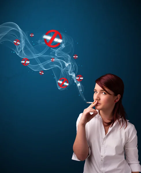 Young woman smoking dangerous cigarette with no smoking signs — Stock Photo, Image