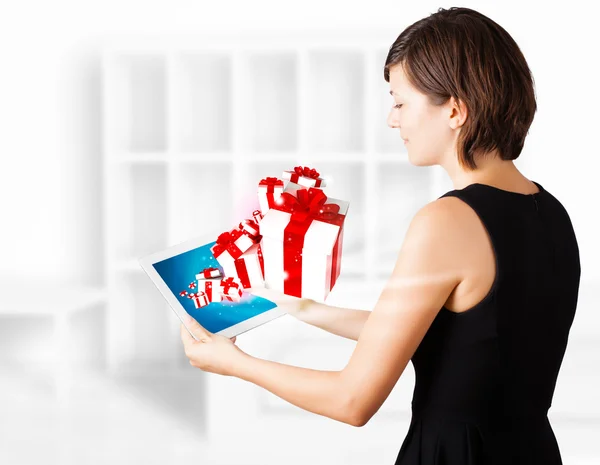 Mujer joven mirando la tableta moderna con cajas de regalo —  Fotos de Stock