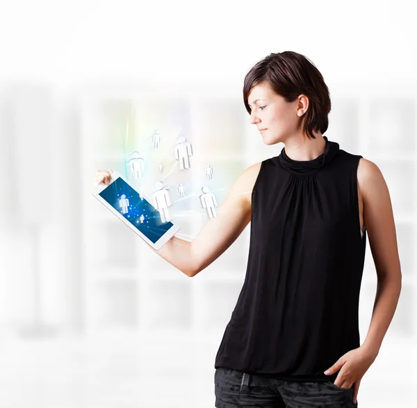 Young woman looking at modern tablet with social icons — Stock Photo, Image