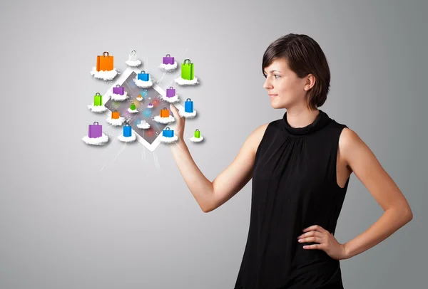 Woman holding modern tablet with colorful shopping bags on cloud — Stock Photo, Image