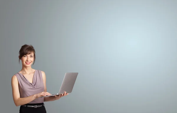 Mulher atraente segurando um laptop com espaço de cópia — Fotografia de Stock