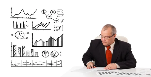 Businessman sitting at desk with statistics and graphs — Stok fotoğraf