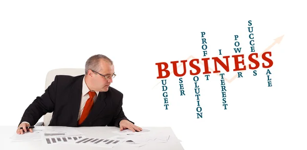 Businessman sitting at desk with word cloud — Stock Photo, Image