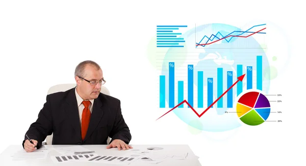 Businessman sitting at desk with statistics — Stock Photo, Image